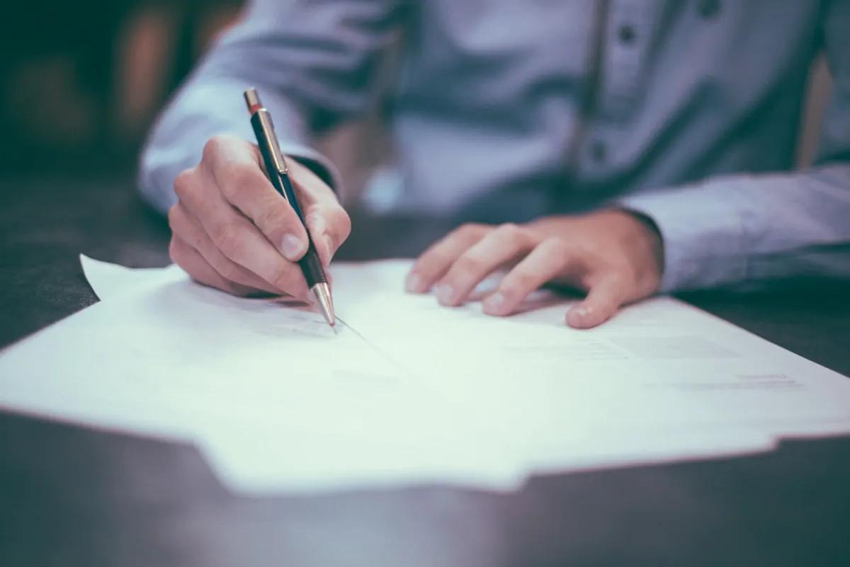 Hands writing on a stack of paperwork — dispatch and payroll done by hand