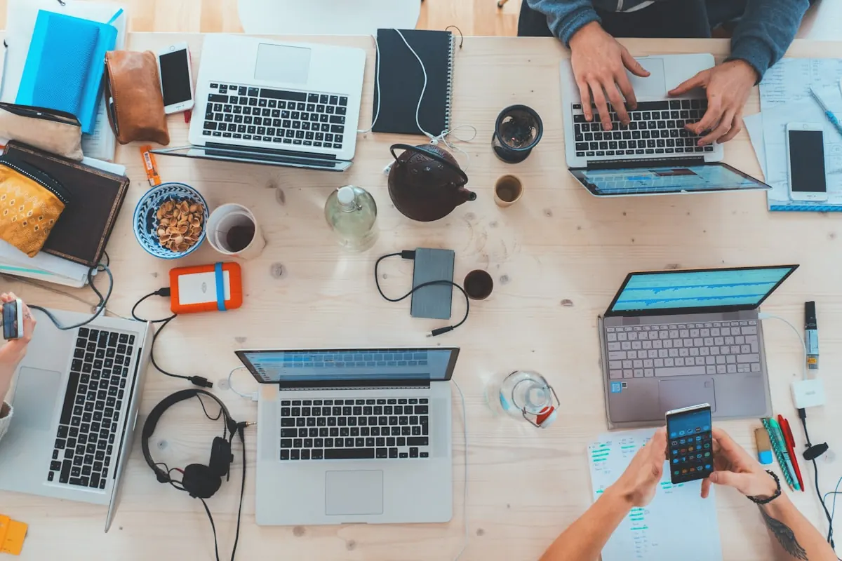 Desk covered in laptops, phones and coffee — the owner running ops by hand