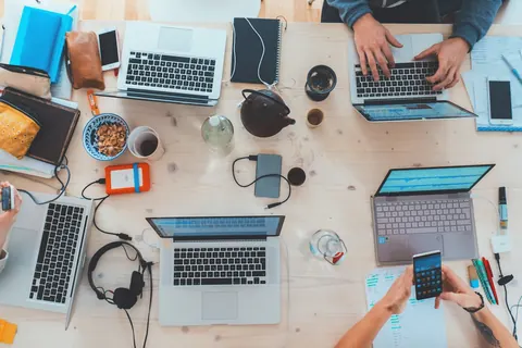 Desk cluttered with laptops and phones — ops by hand