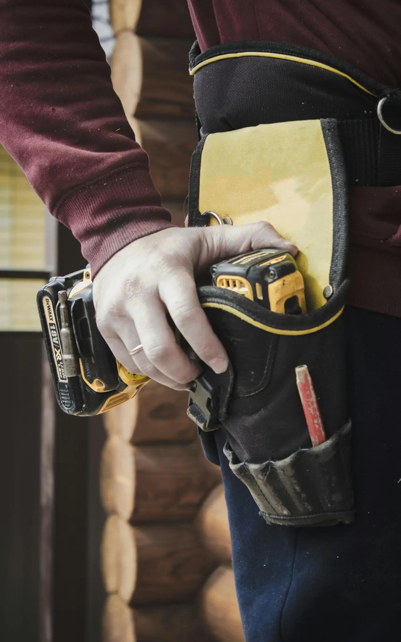 A handyman with a tool belt and cordless drill on a job