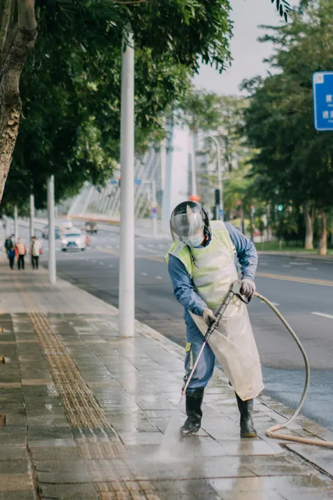 Worker spraying water on a hard surface — pressure washing