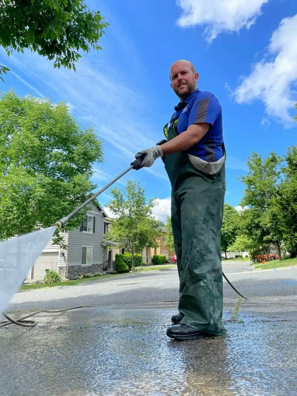 A worker pressure washing a surface with a high-pressure water wand