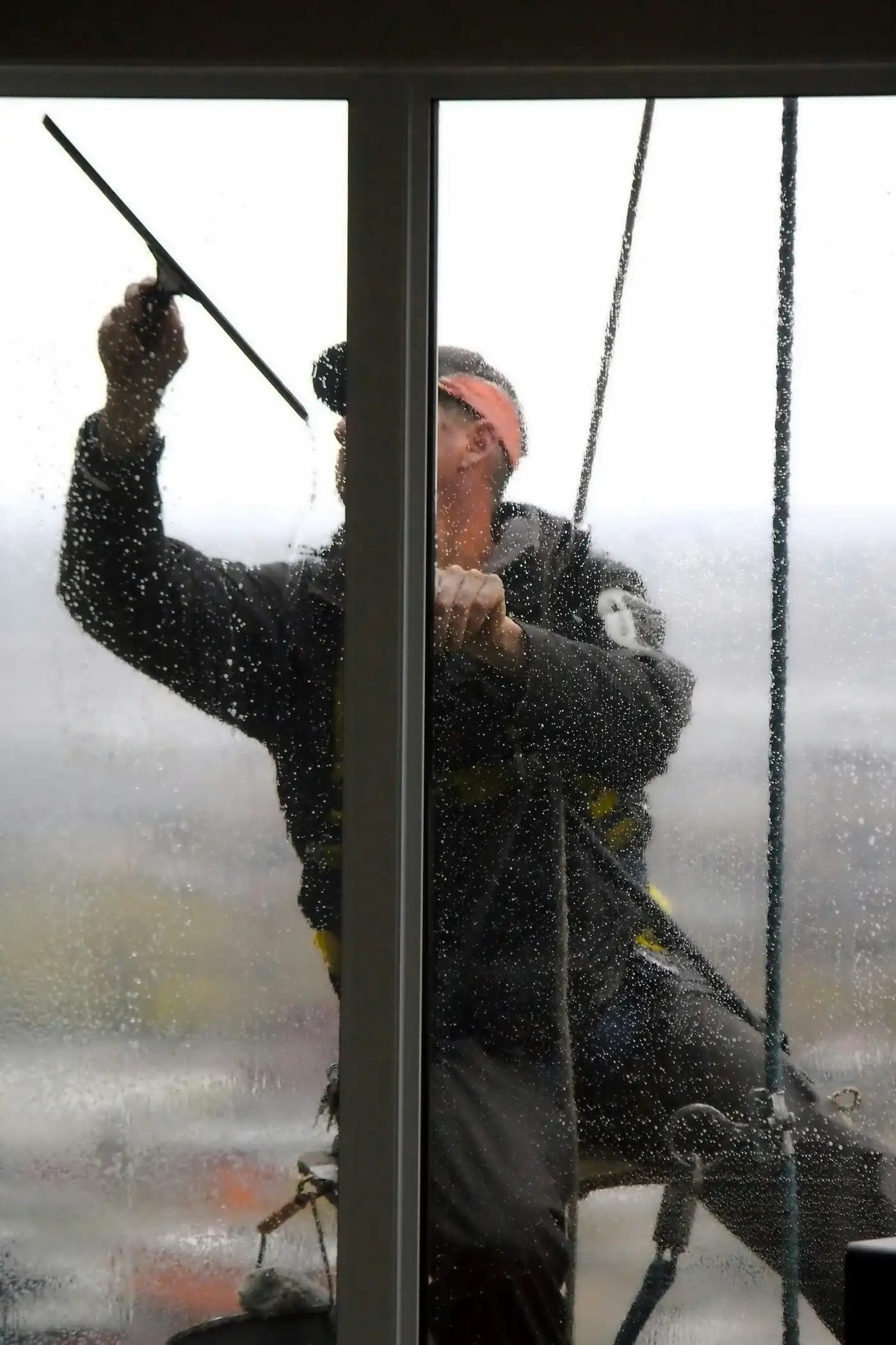 A window cleaner squeegeeing a glass pane clean